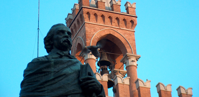 La statua di Quirico Filopanti con lo sfondo della torre del Palazzo comunale